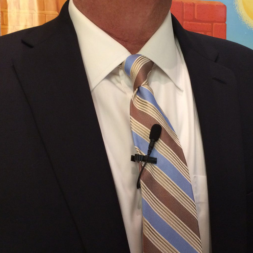 Acacia Audio Platinum Lavalier microphone – a compact, clip-on lapel mic with a sleek black design, wired connection, and foam windscreen, designed for clear audio recording in professional or mobile setups shown on tie